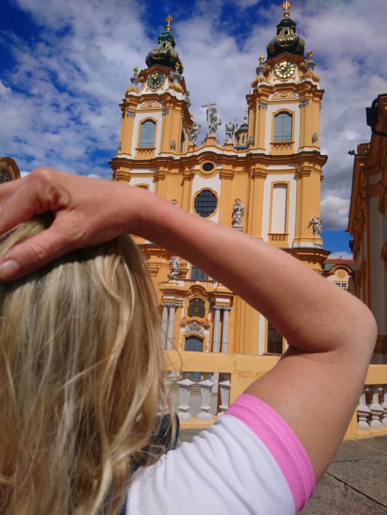 Greta Rosa vor dem Benediktinerstift Melk. Nach Jahrhunderten bewegender Geschichte erlebte das Kloster Melk zu Beginn des 18. Jahrhunderts eine glanzvolle Blüte: Unter dem Abt Berthold Dietmayer schuf der Baumeister Jakob Prandtauer einen monumentalen barocken Prachtbau, der sicher als Ausdruck eines neuen Lebensgefühls, eines gestärktem Herrschaftswillens sowohl der Kirche als auch der Habsburger zu sehen ist. Ein wunderschönes Zusammenspiel aus Landschaft, Bauwerk und Fluss!