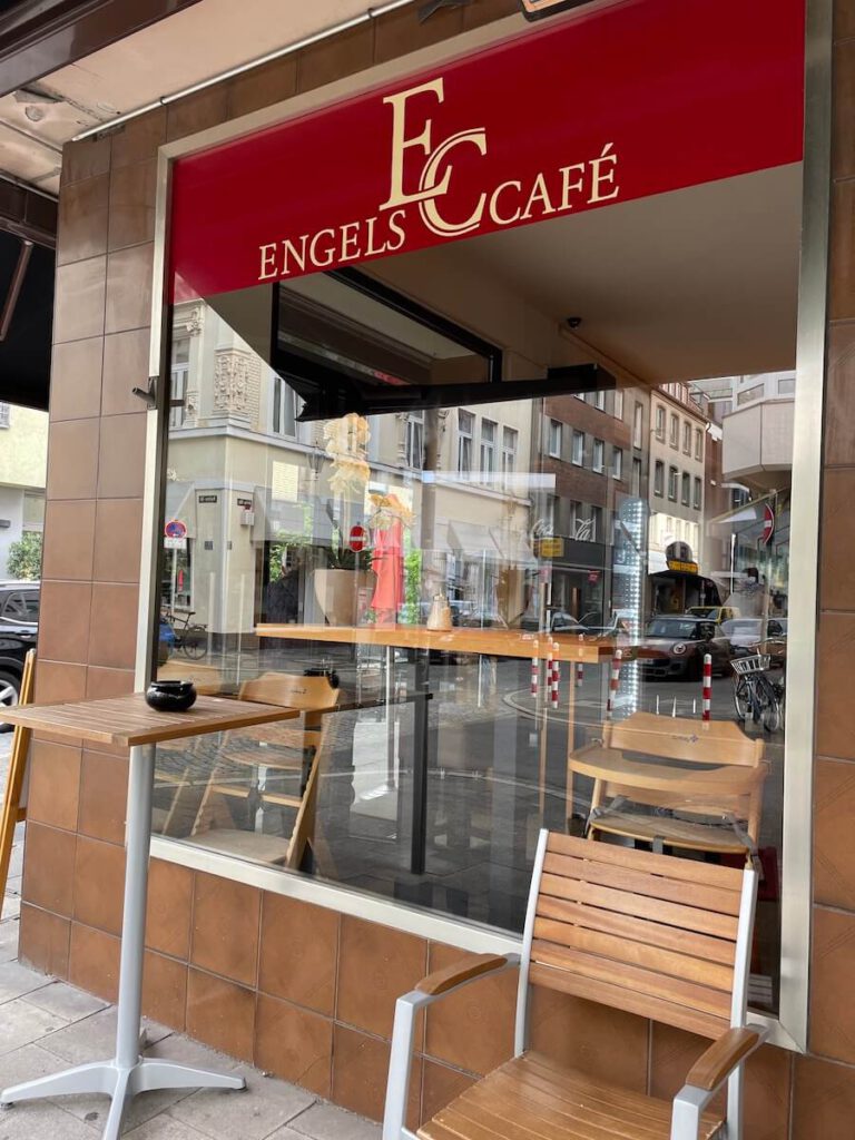 Engels Café in der Carlstadt in Düsseldorf. Seiliche Ansicht mit Stühlen und Tischen zu, draussen sitzen.