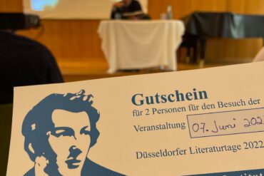 Alexander Kluge zu Gast im Palais Wittgenstein, Düsseldorf; Im Vordergrund ist ein Gutschein über zwei Eintrittskarten zu sehen.